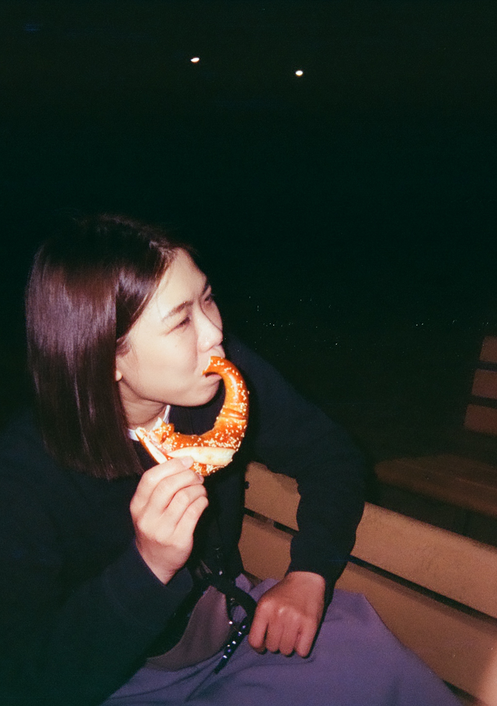 A short-haired woman eating a pretzel.