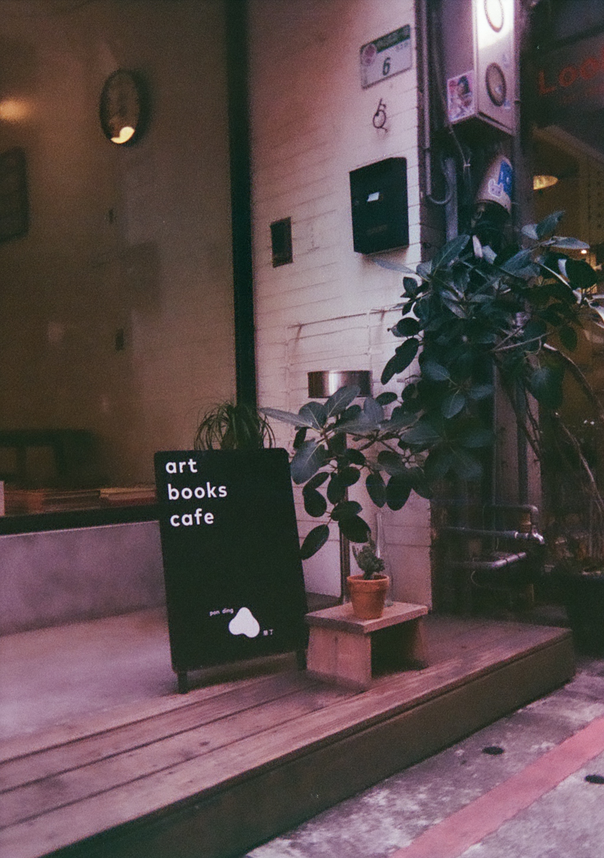 A black and white floor shop sign that says art, books, cafe, pon ding