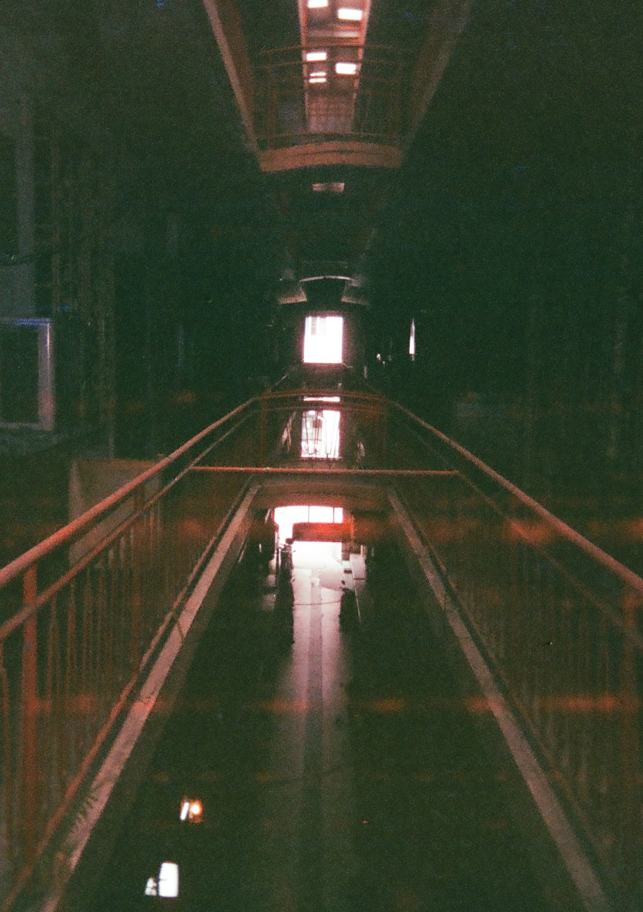 a walkway with a railing and a light in the distance