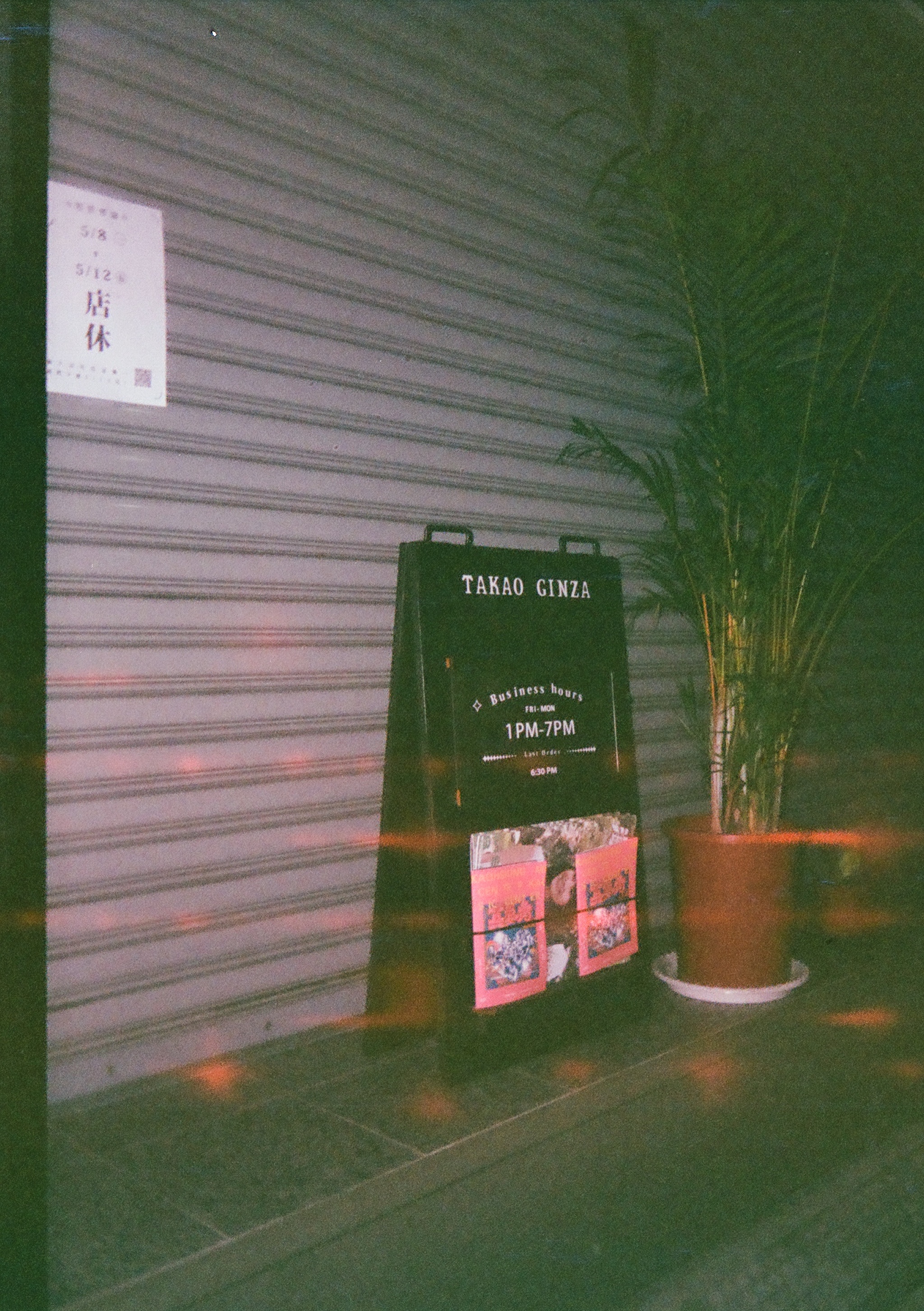 a sign reading Takao Ginza next to a plant