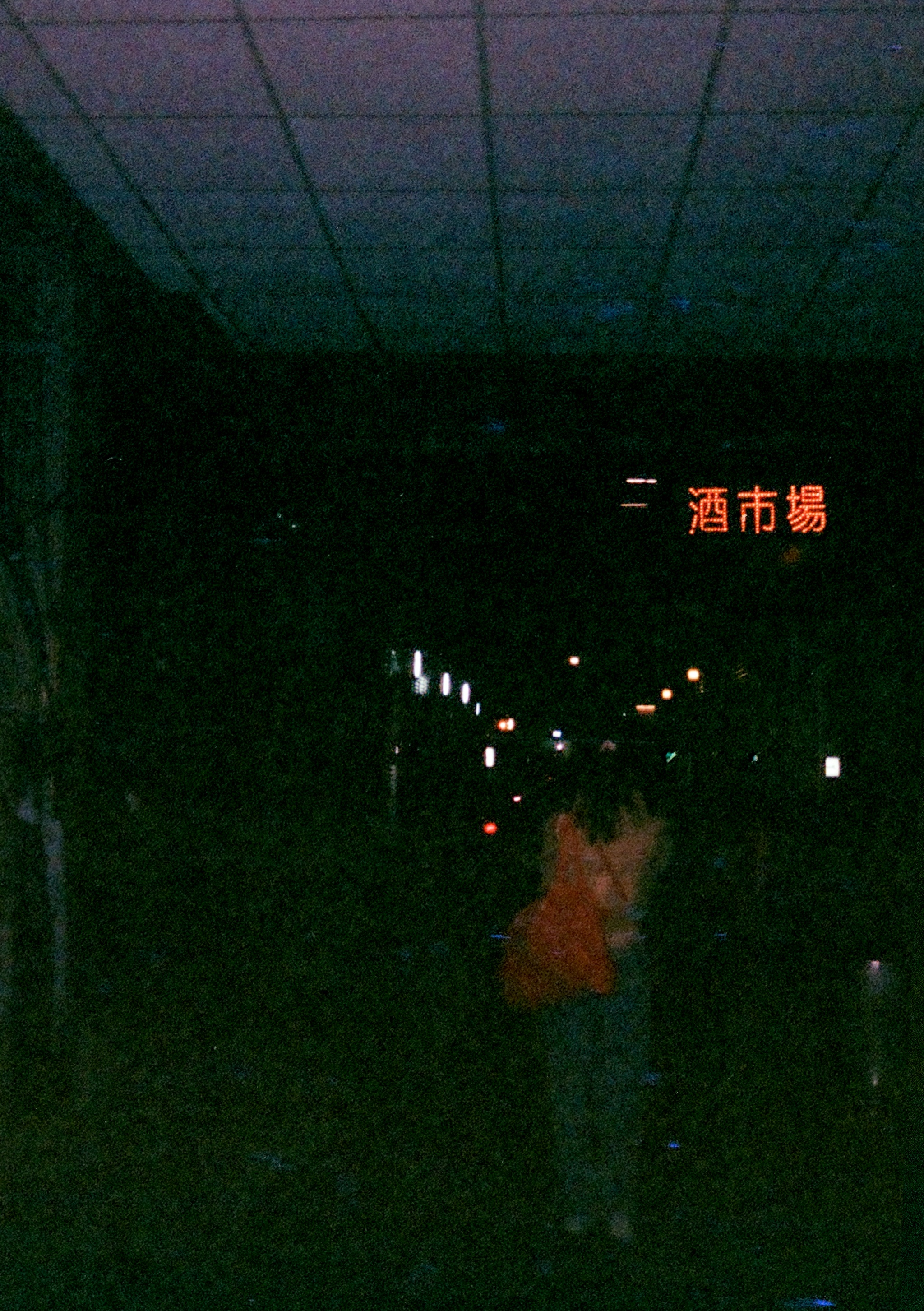 a person walking in a dark alley with a neon sign for Wine Market above them