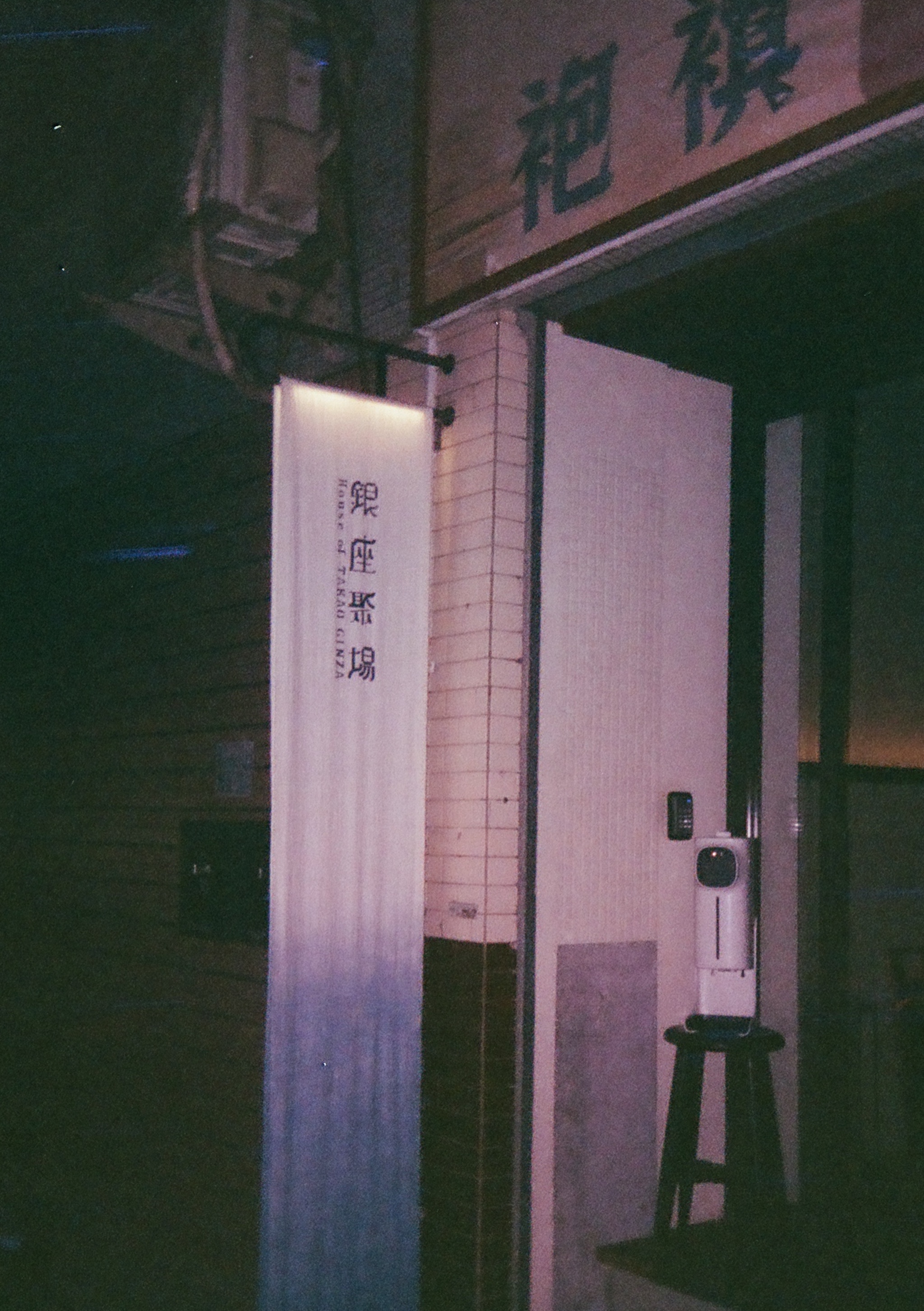 a white textile sign reading Ginza Gathering Place and a hand sanitizer machine