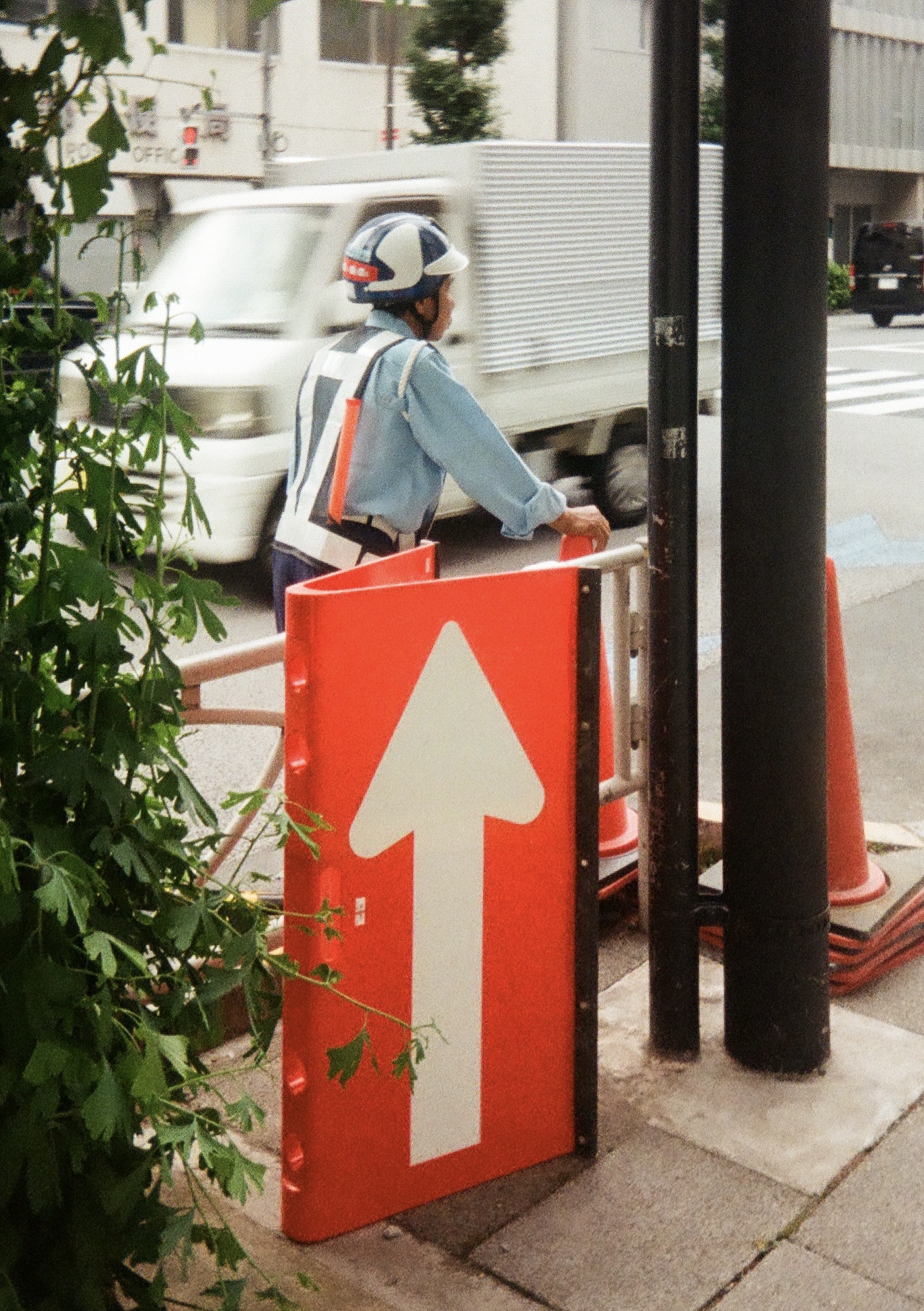 An orange arrow sign pointing up and a person with worker attire