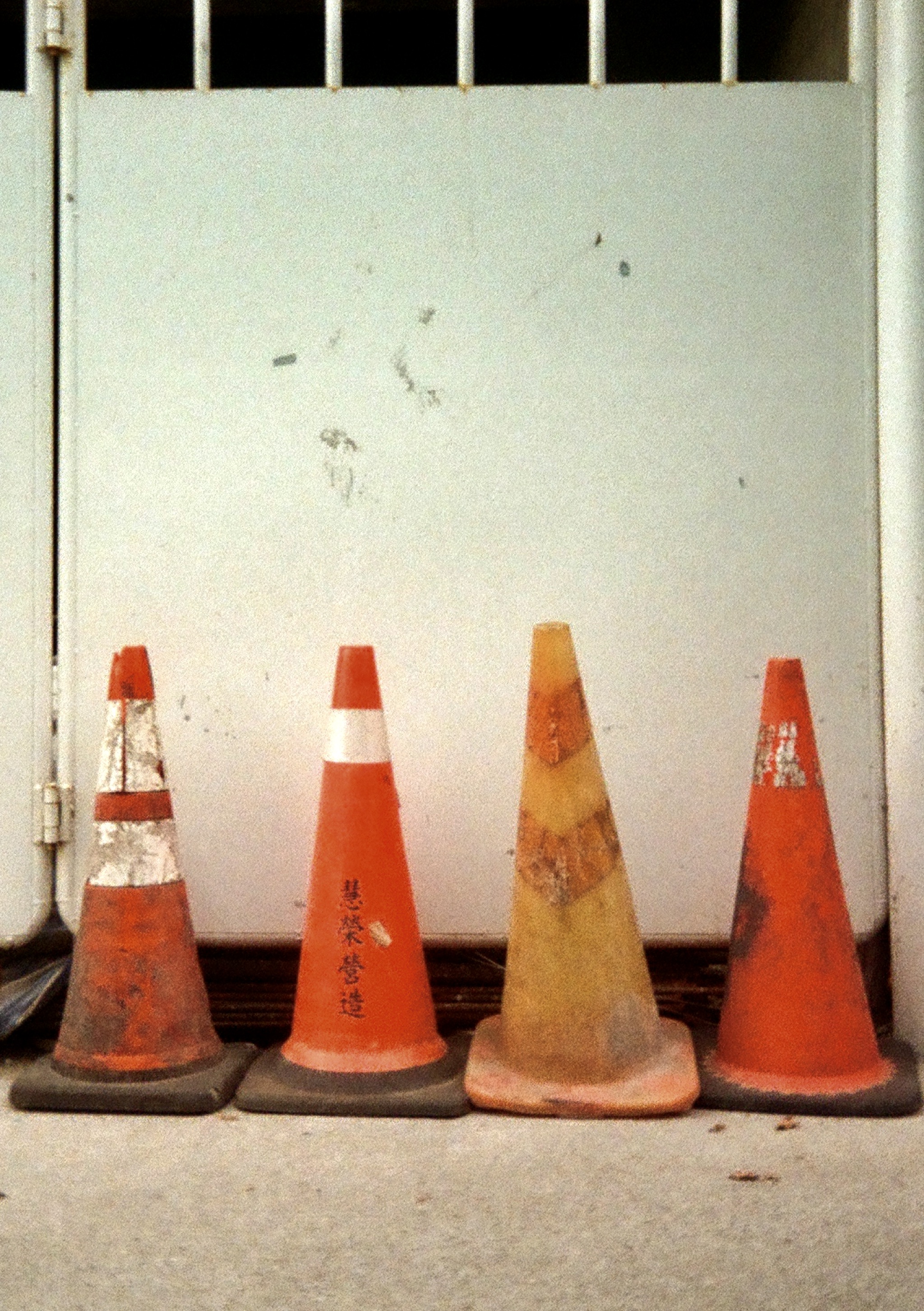 Four traffic cones in front of a white metal door