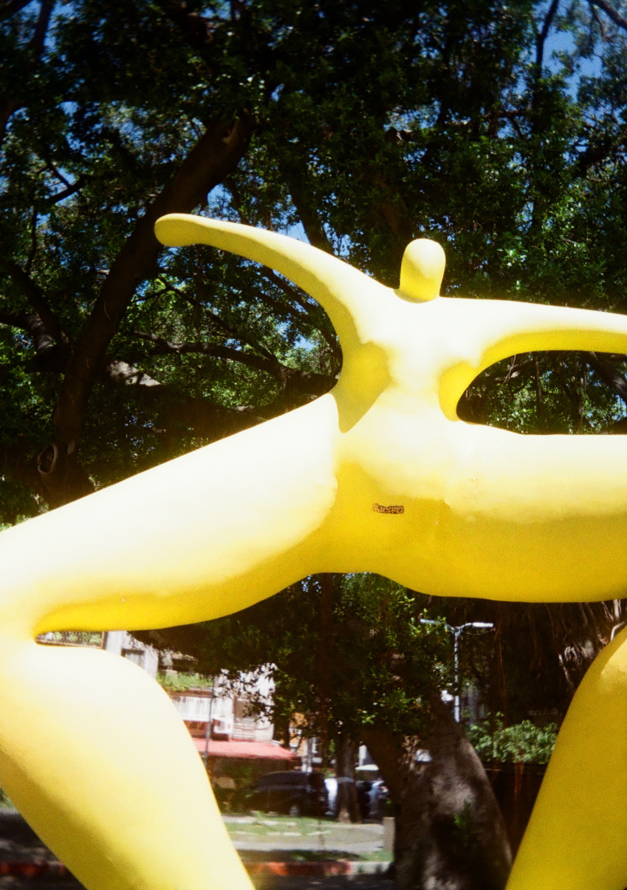 A bright yellow statue with a sticker on the crutch area